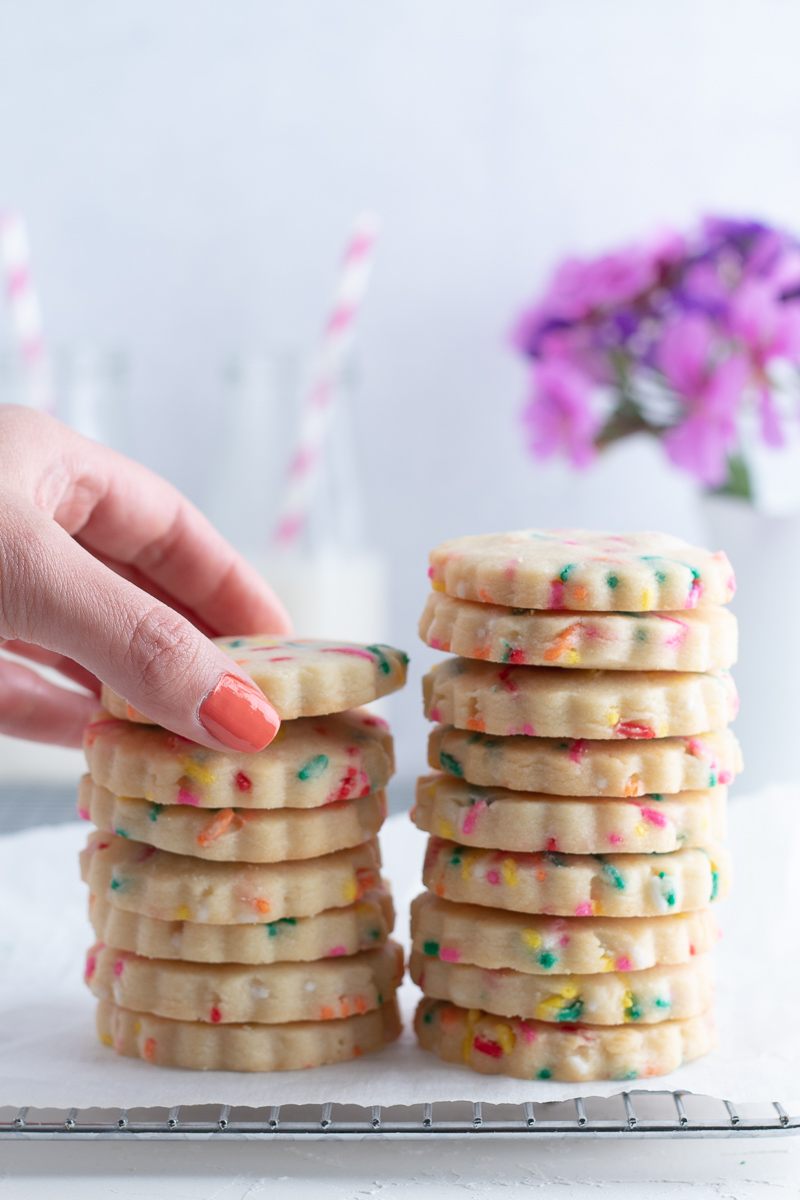 A hand reaching for a cookies from a tall stack of cookies