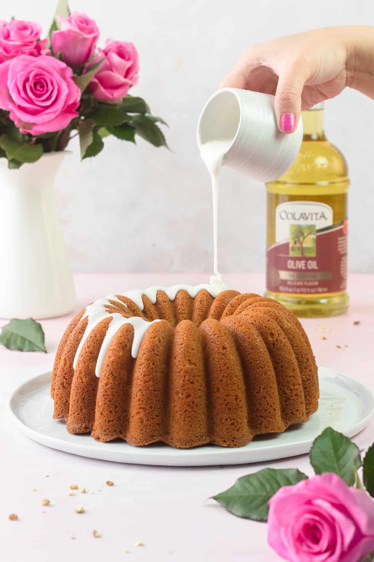Pistachio Olive Oil Cake is being drizzled with the rose glaze
