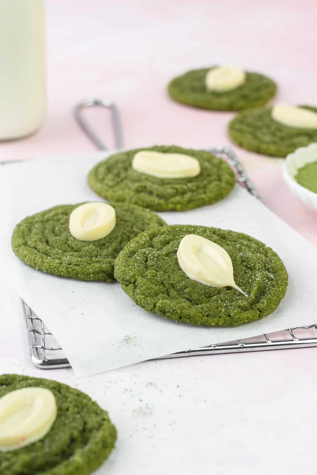 Matcha White Chocolate Cookies on a rack and milk in the back.