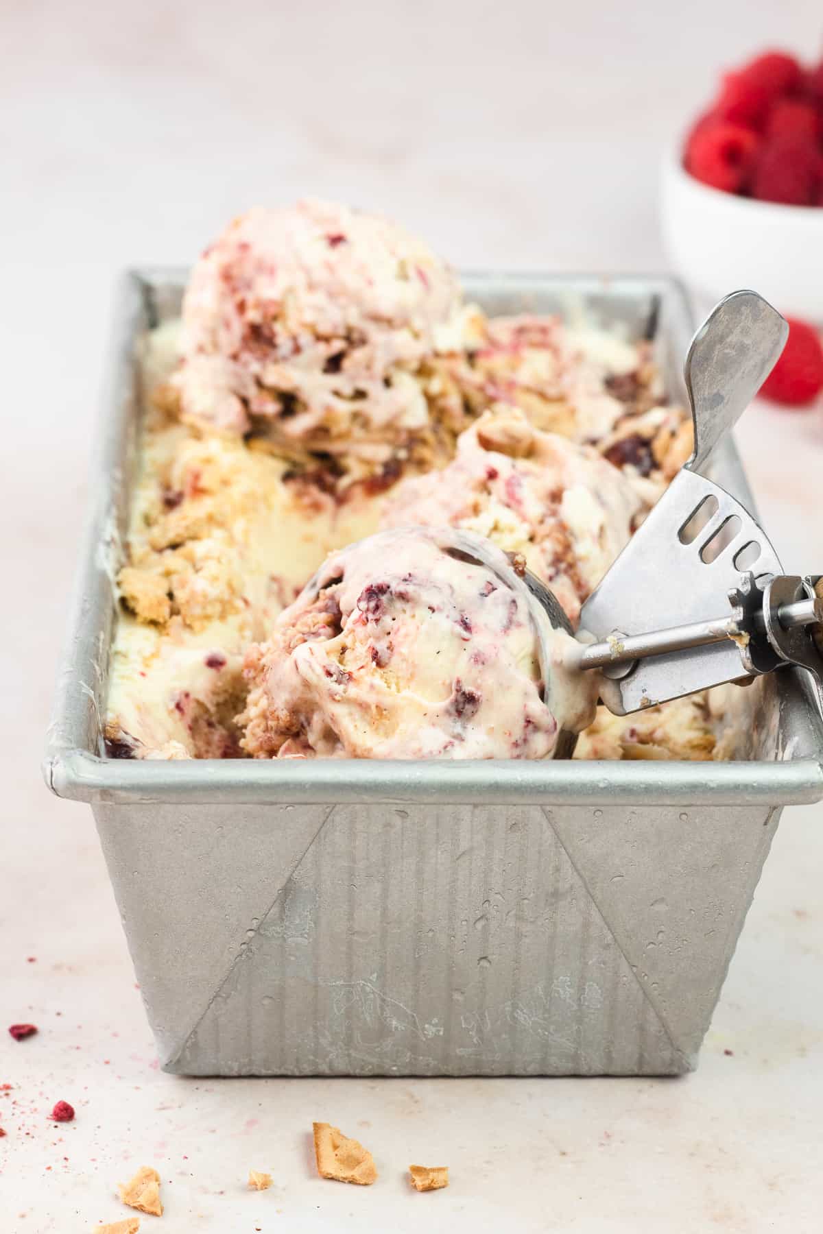 Raspberry Cheesecake Ice Cream in loaf pan with an ice cream scoop on top