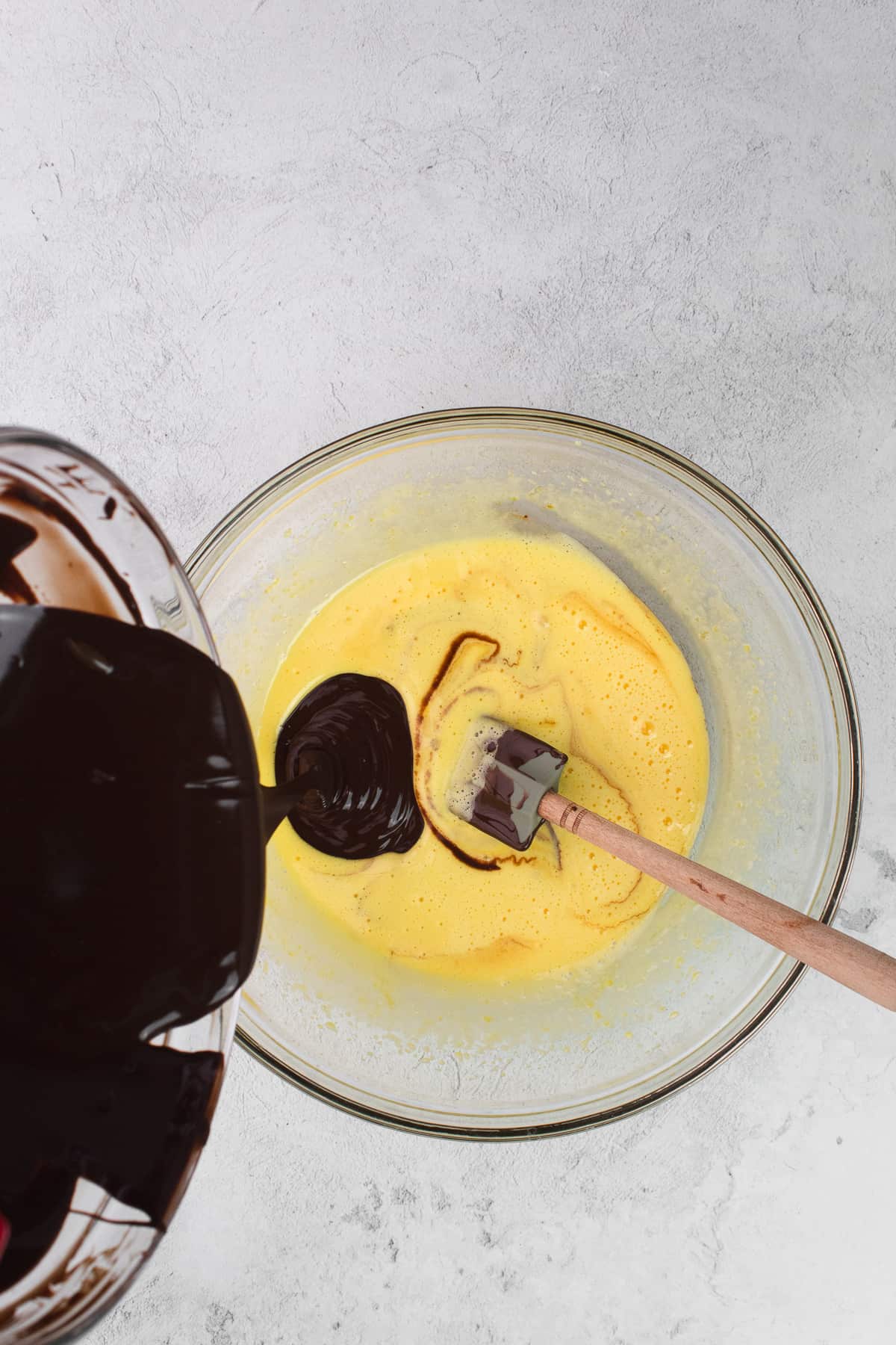 Melted chocolate is added into the bowl of whipped egg yolks