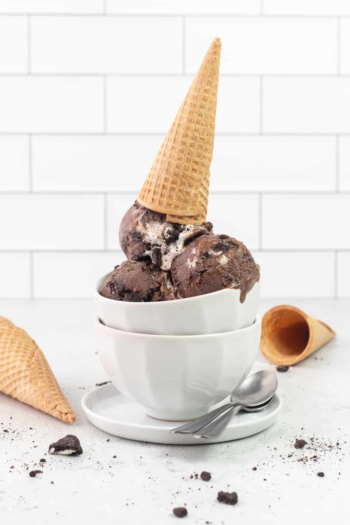 Chocolate Ice Cream with Oreos and Marshmallow in stacked bowls with ice cream cones all around