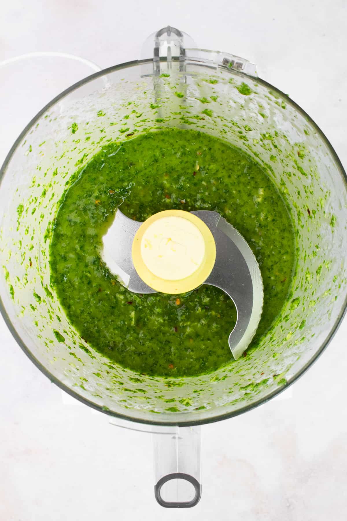 Basil olive oil sauce in the bowl of a food processor
