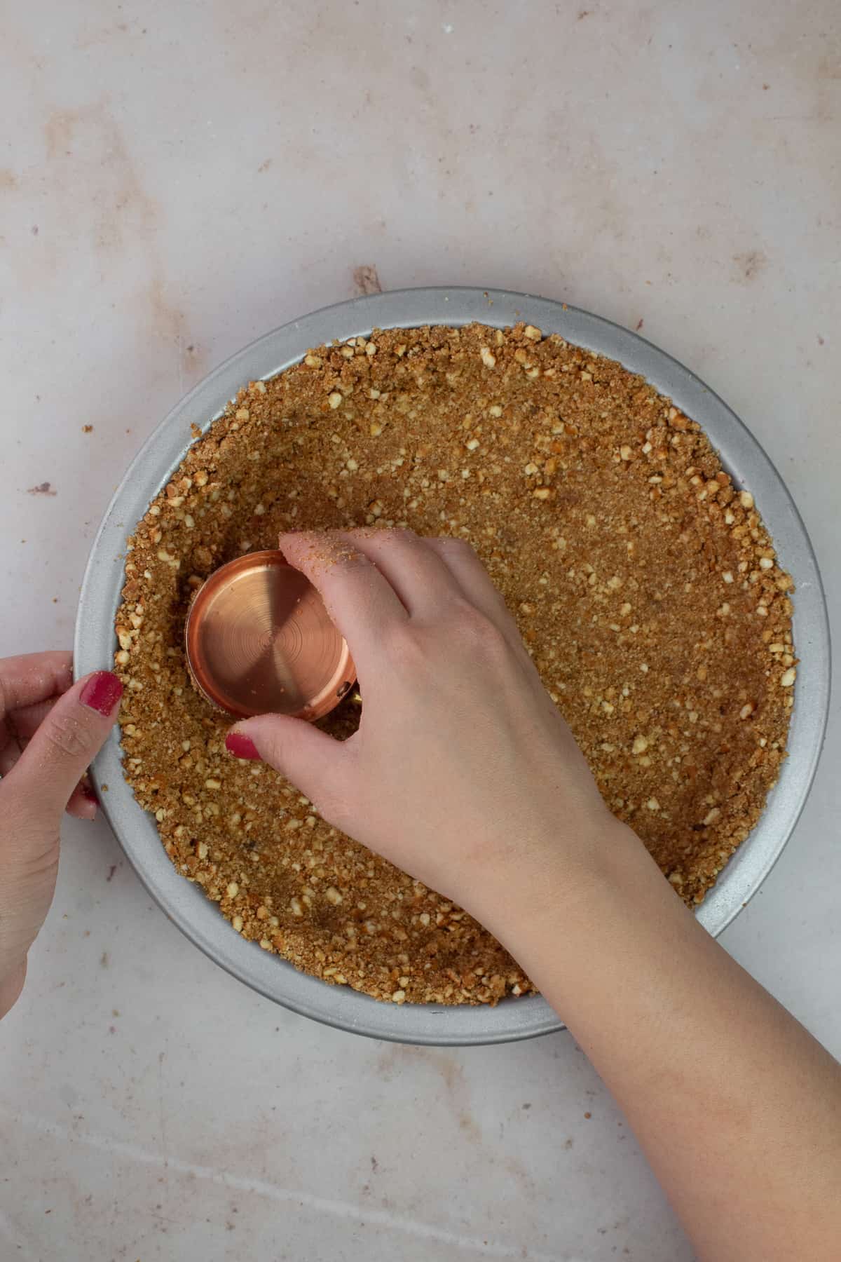 Hand pressing pretzel crust into pie pan