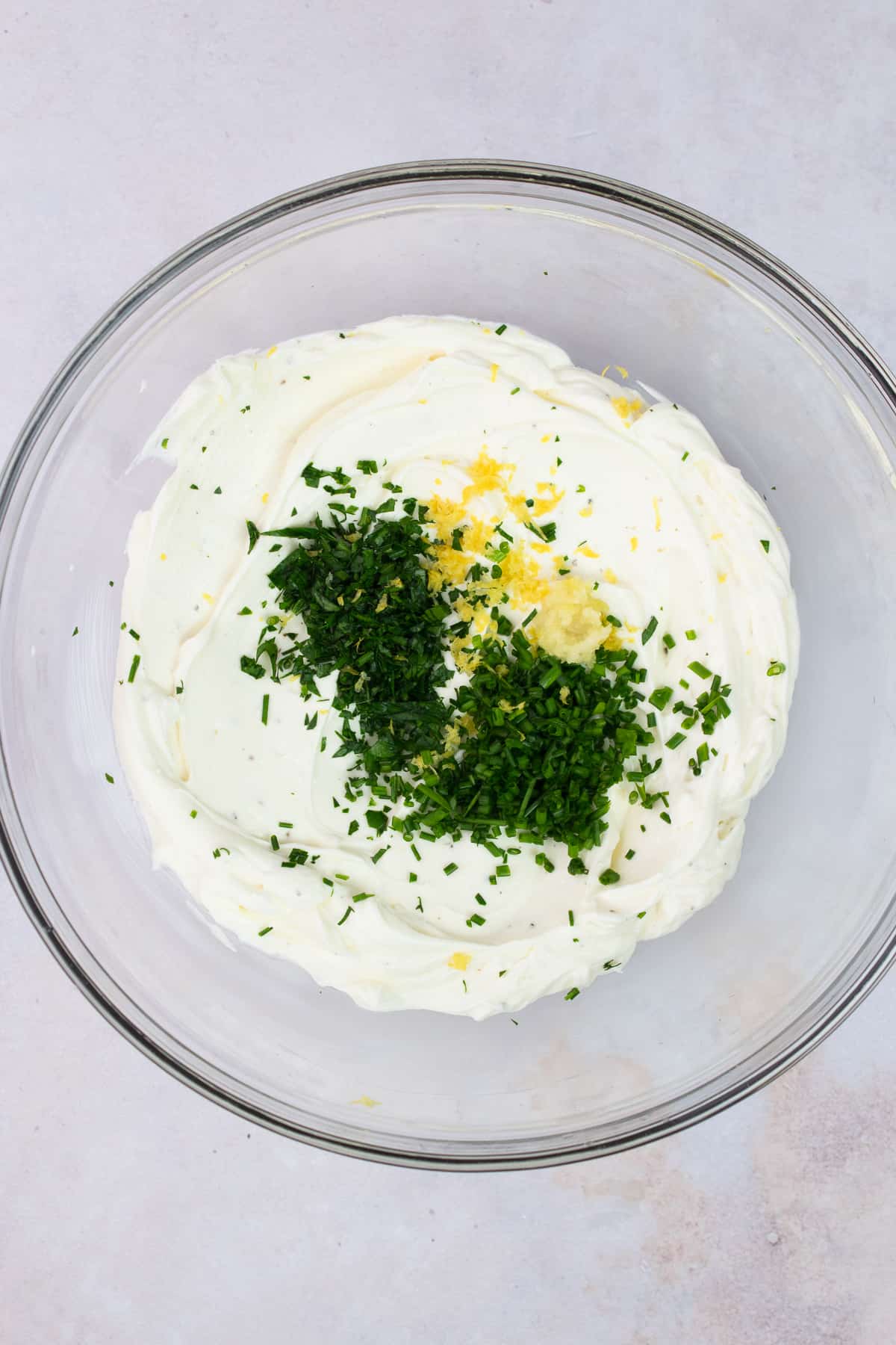 A bowl of whipped cream cheese with chives, parsley, lemon zest and garlic