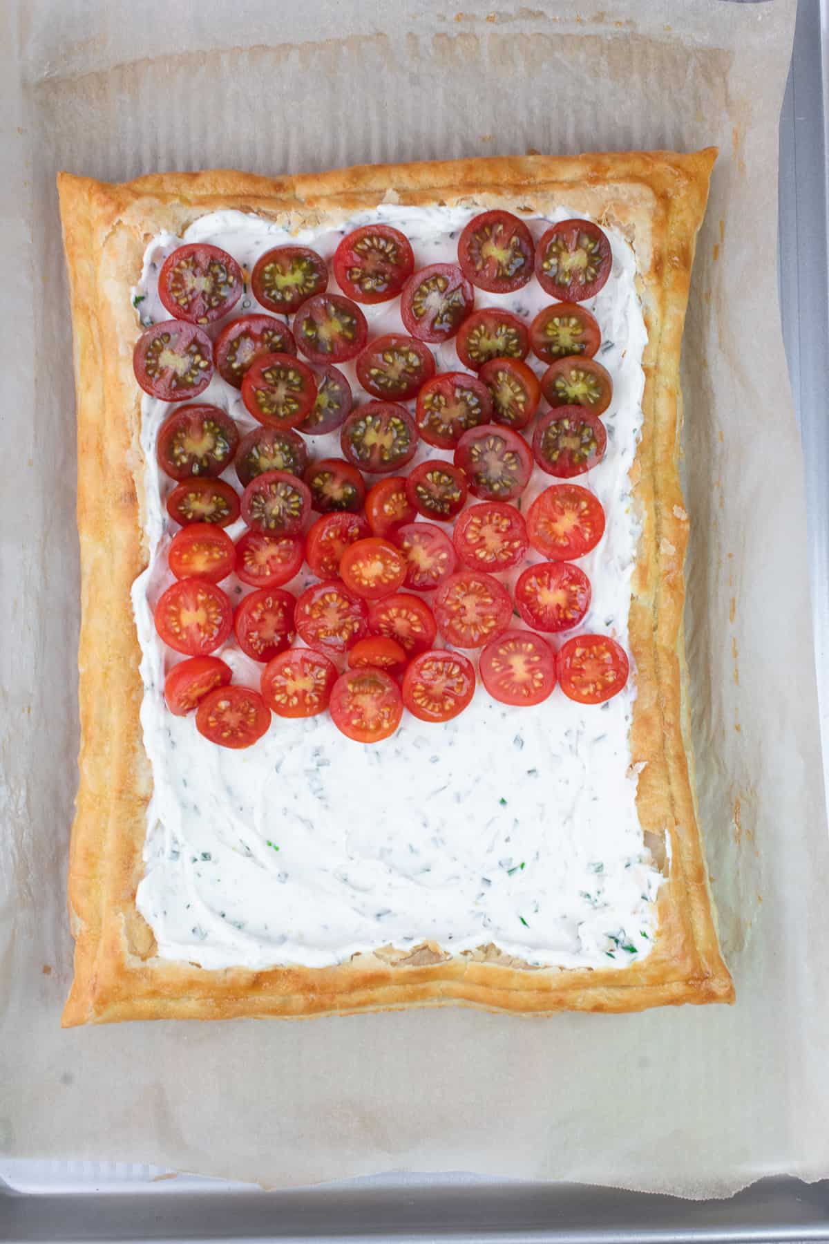 Golden brown puff pastry with a layer of herbed cream cheese and raw tomatoes