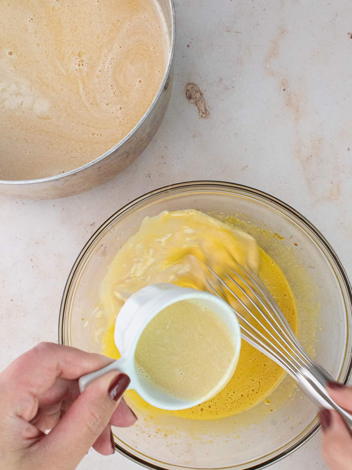 pouring hot cream into egg yolk mixture