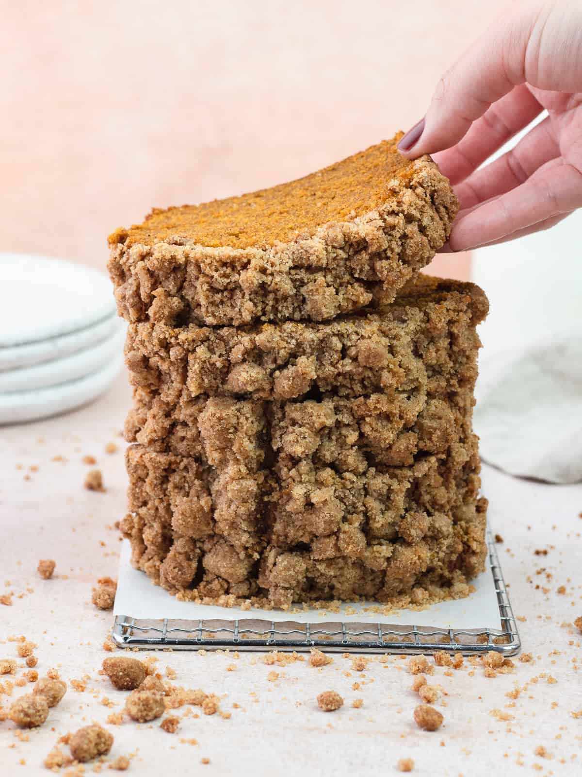 Hand grabbing a piece of pumpkin bread from a stack of slices