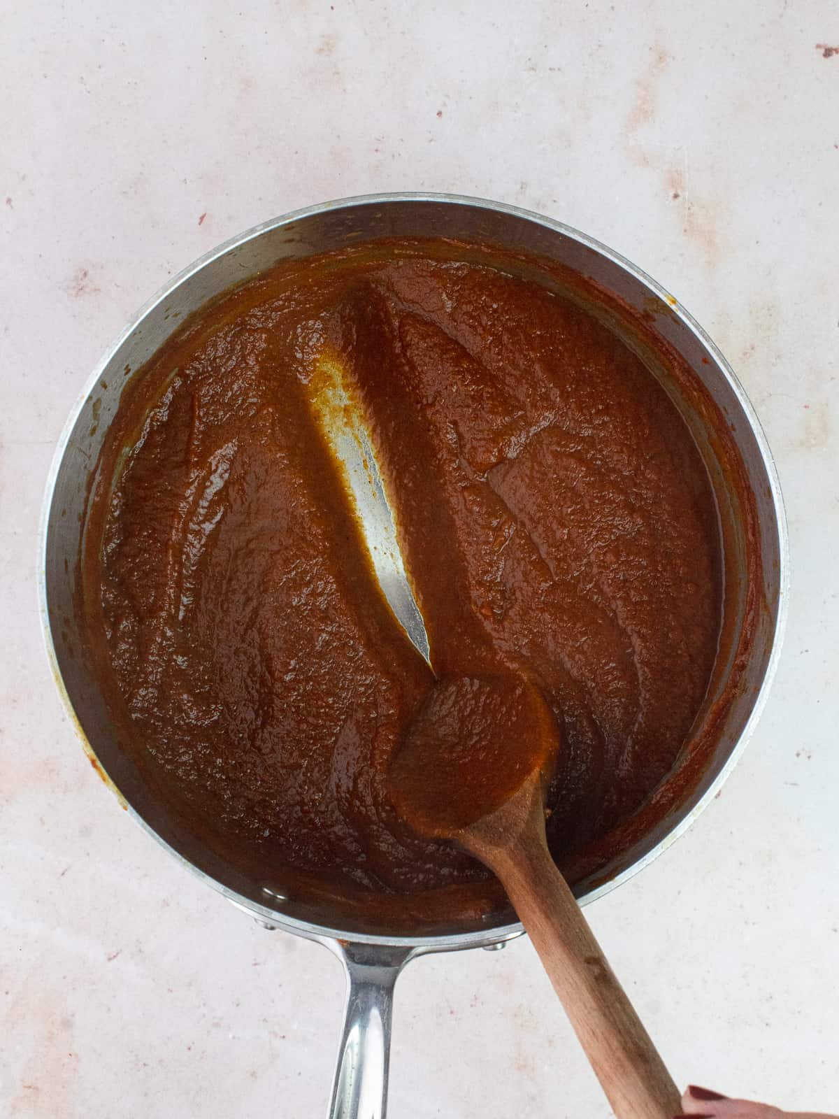 Wooden spoon in saucepan filled with pumpkin butter