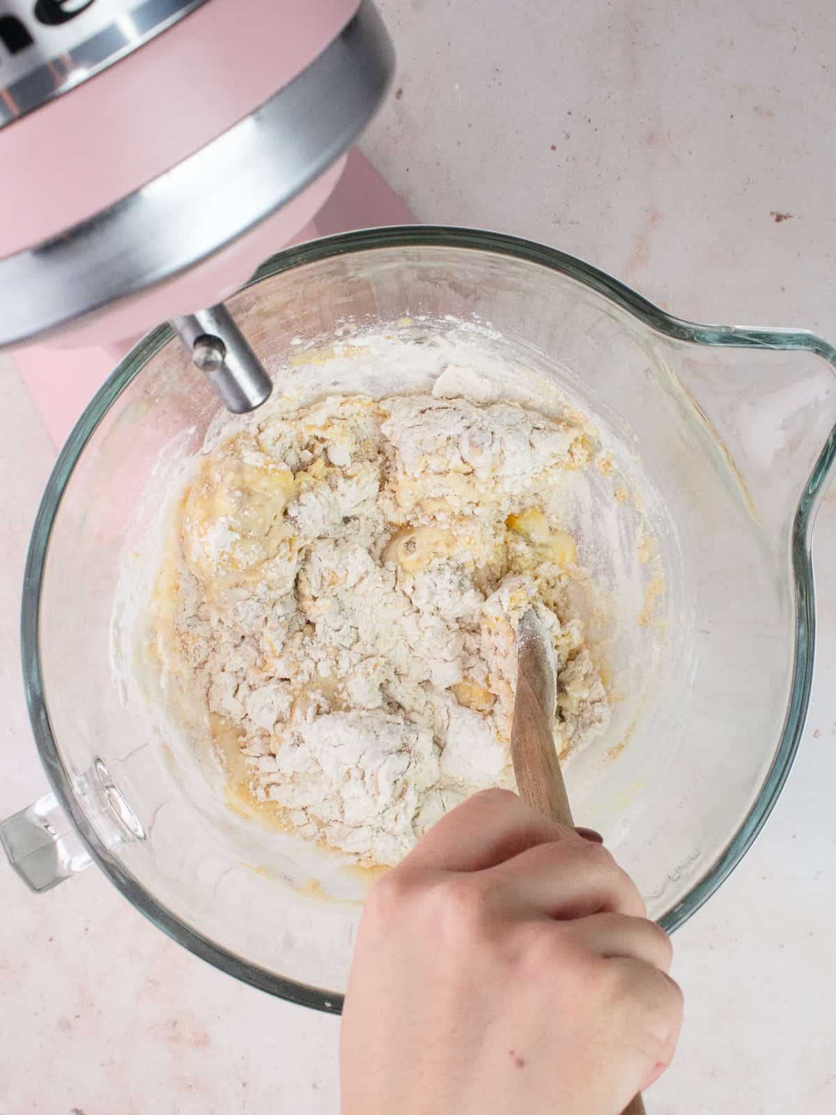 Hand mixing dough together with wooden spoon