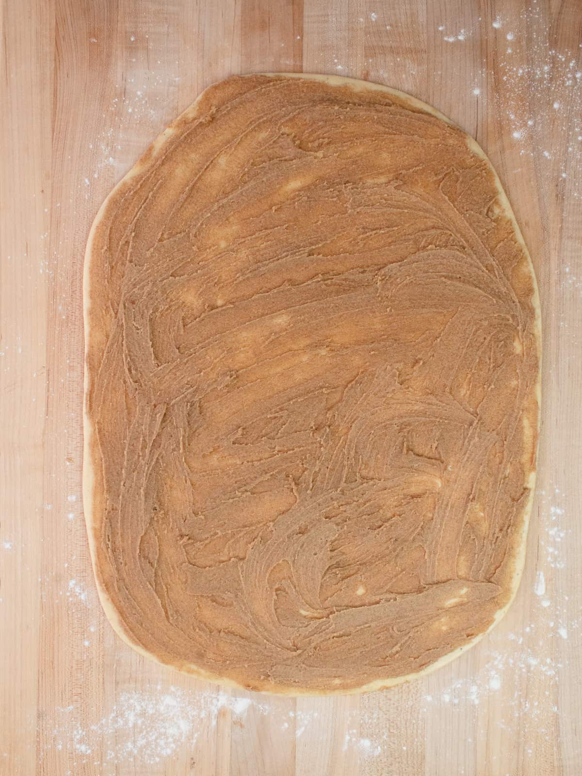 Dough rolled into a rectangle and has a layer of cinnamon filling on top