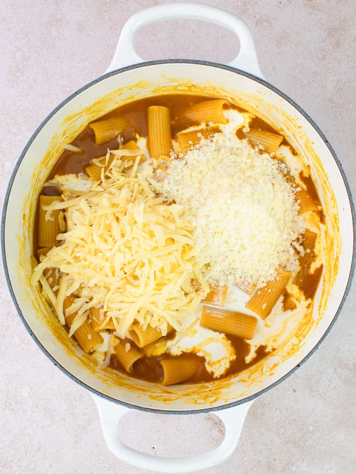 Cheesy pumpkin rigatoni in pot with parmesan and shredded gouda