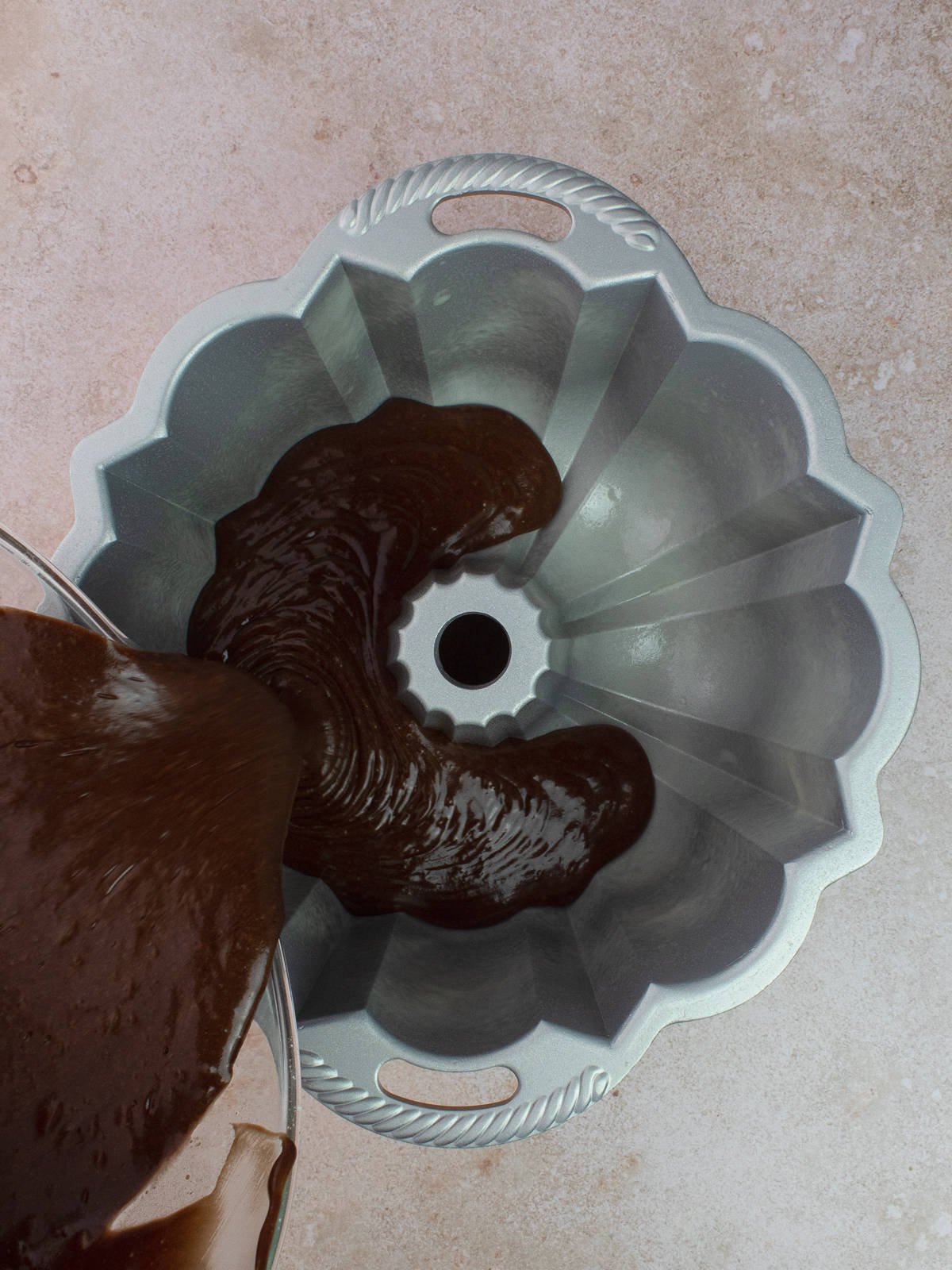 Pouring chocolate olive oil cake batter into bundt pan