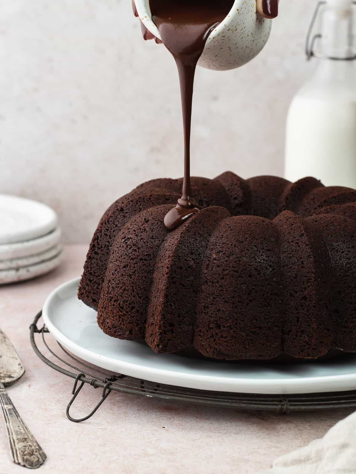 Pouring chocolate ganache on chocolate olive oil cake