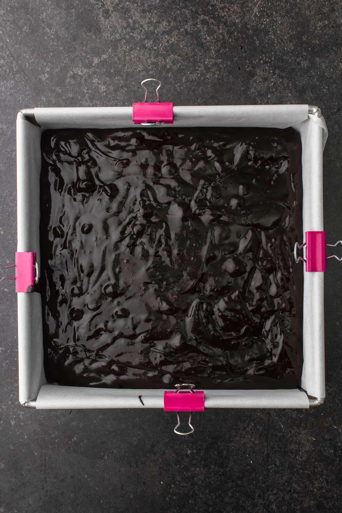 Brownies batter in parchment-lined square baking pan