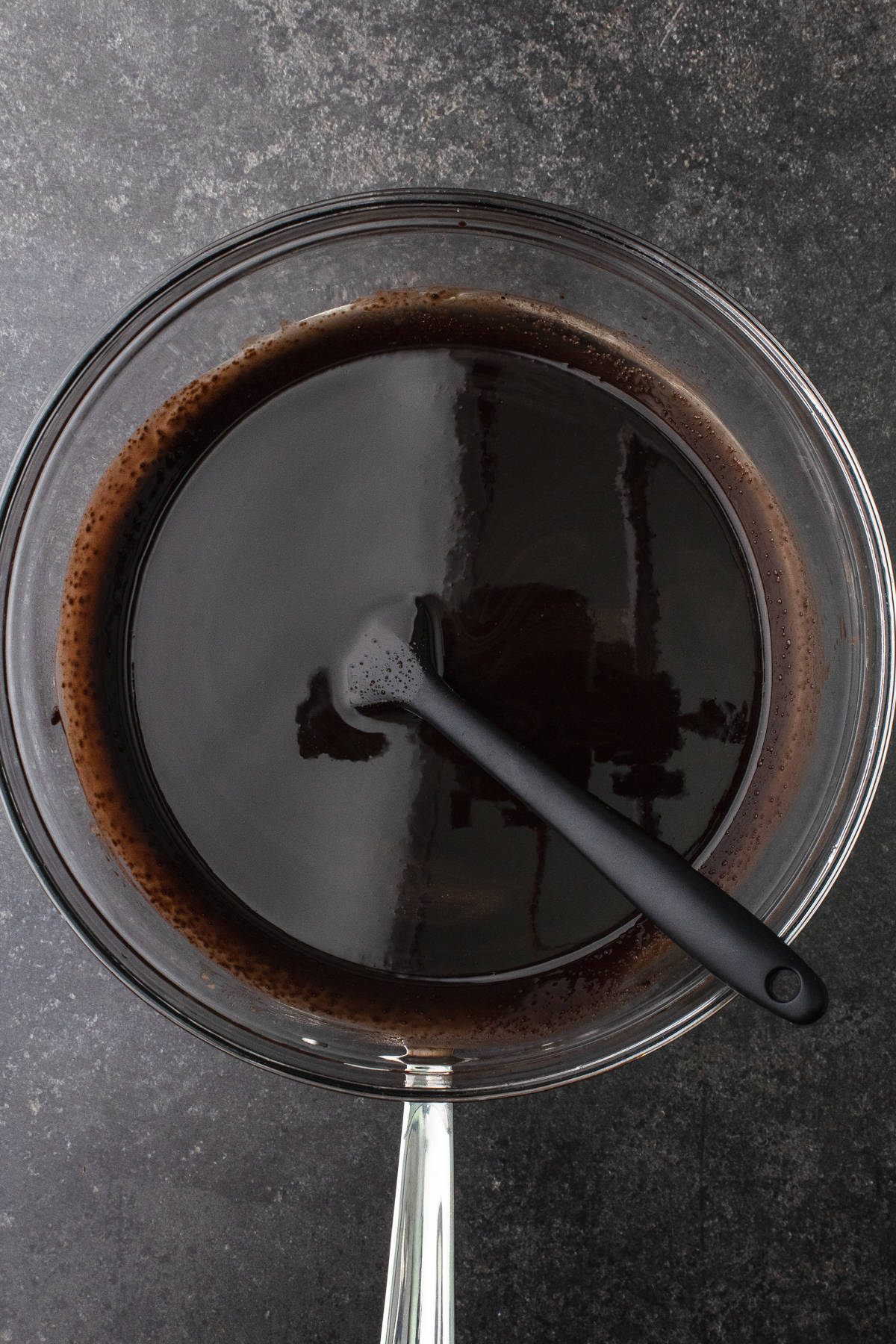 Melted chocolate, cocoa powder, espresso powder and olive oil in a glass bowl over a saucepan of simmering water
