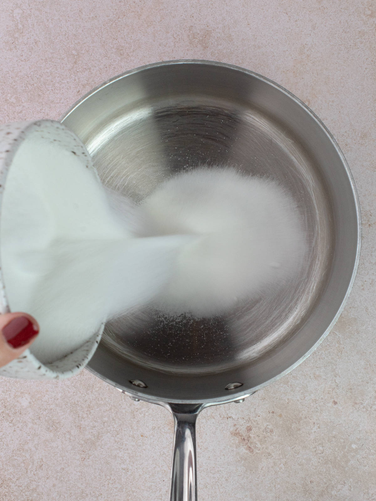 White sugar is added to a clean saucepan