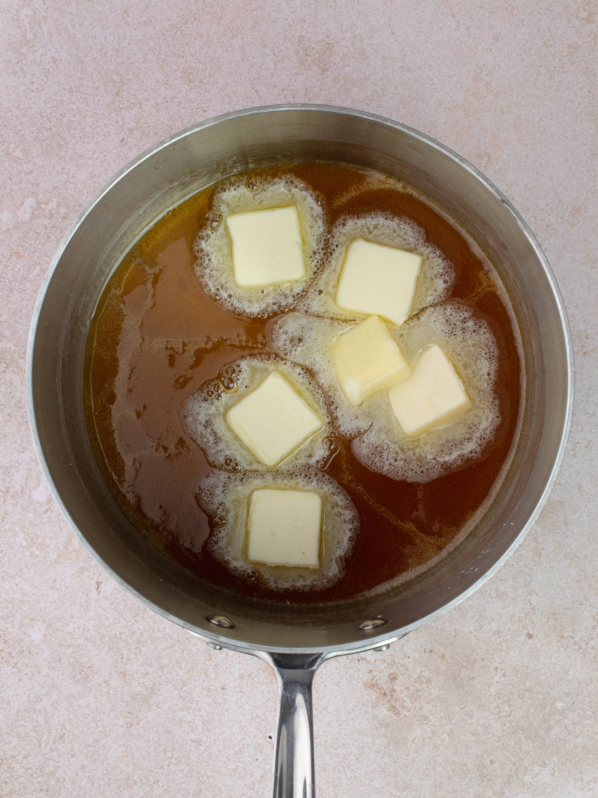 Pieces of butter added to melted sugar