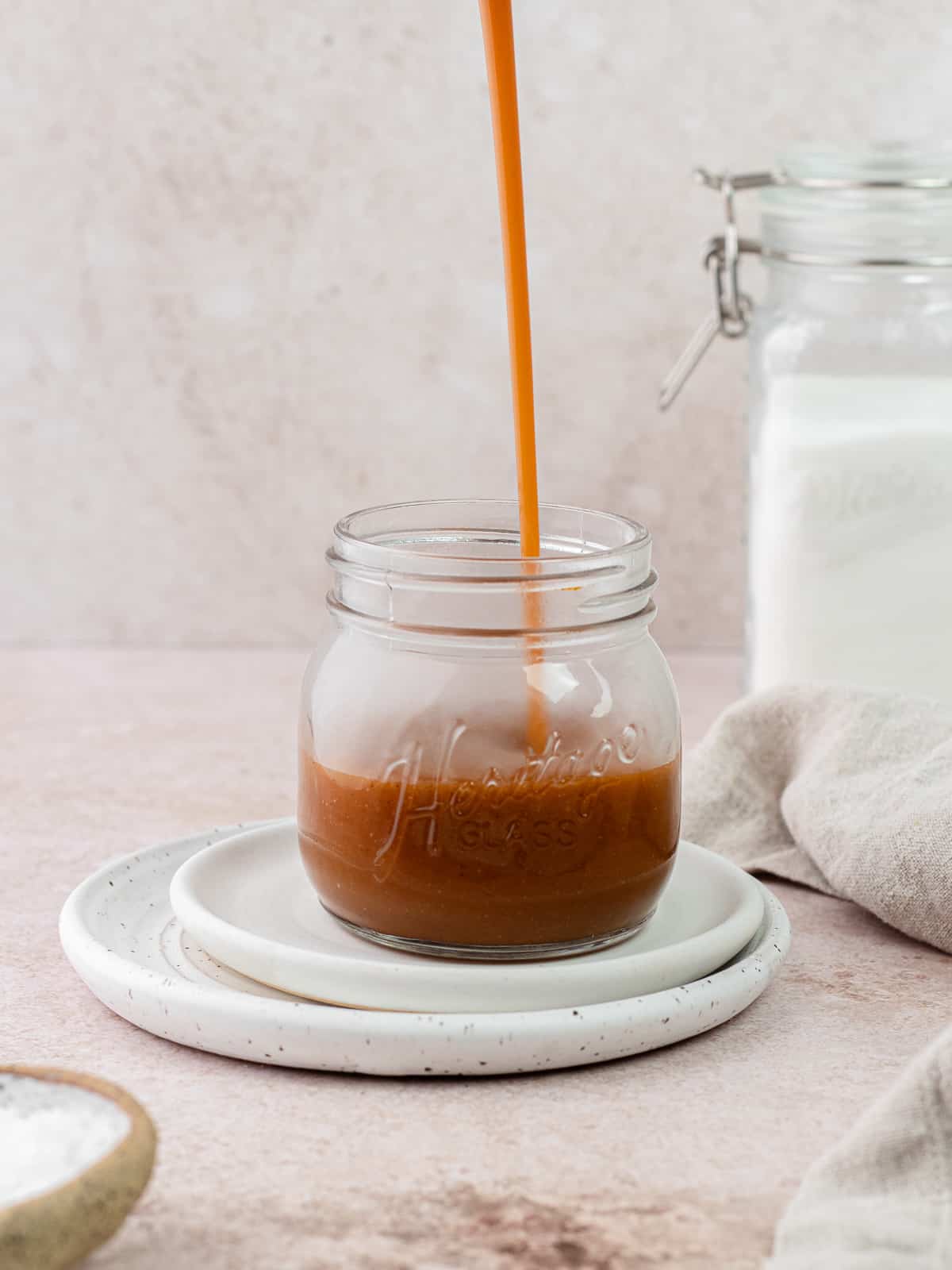 Salted caramel sauce being poured into glass jar