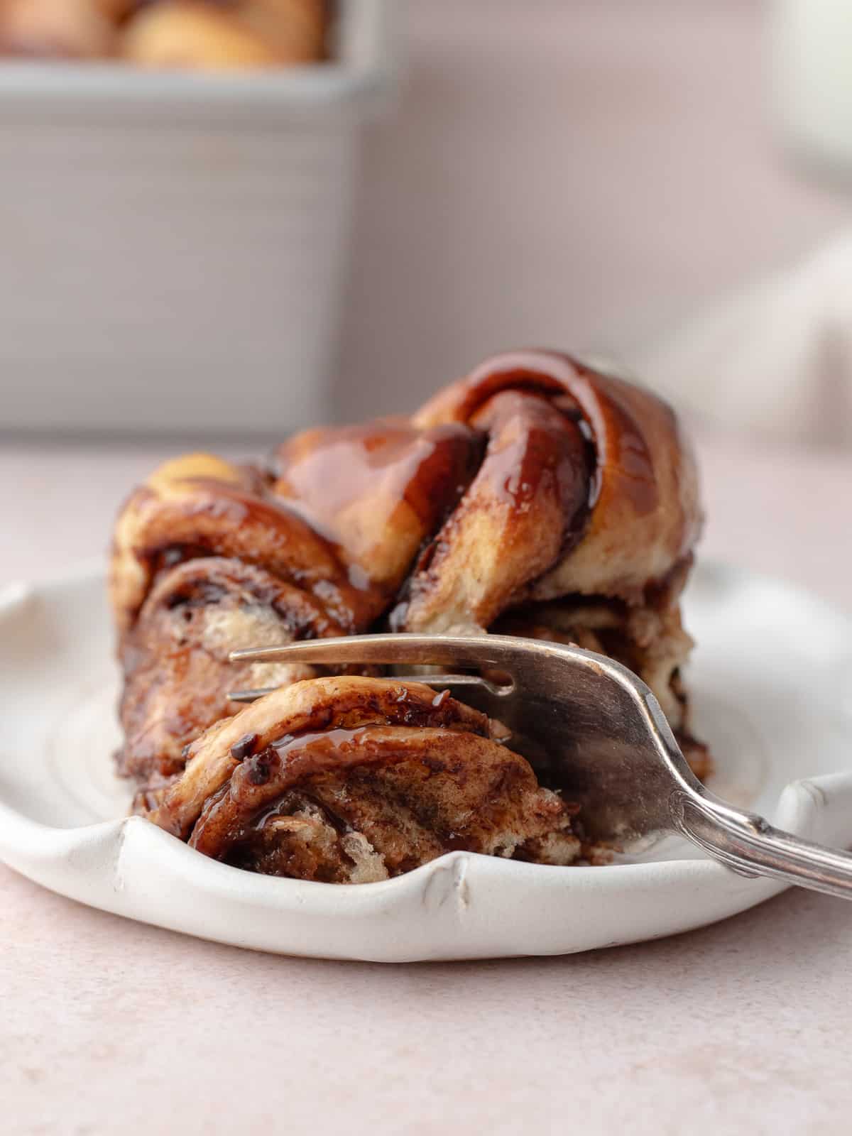 A piece of Nutella knot bun on a plate with a fork