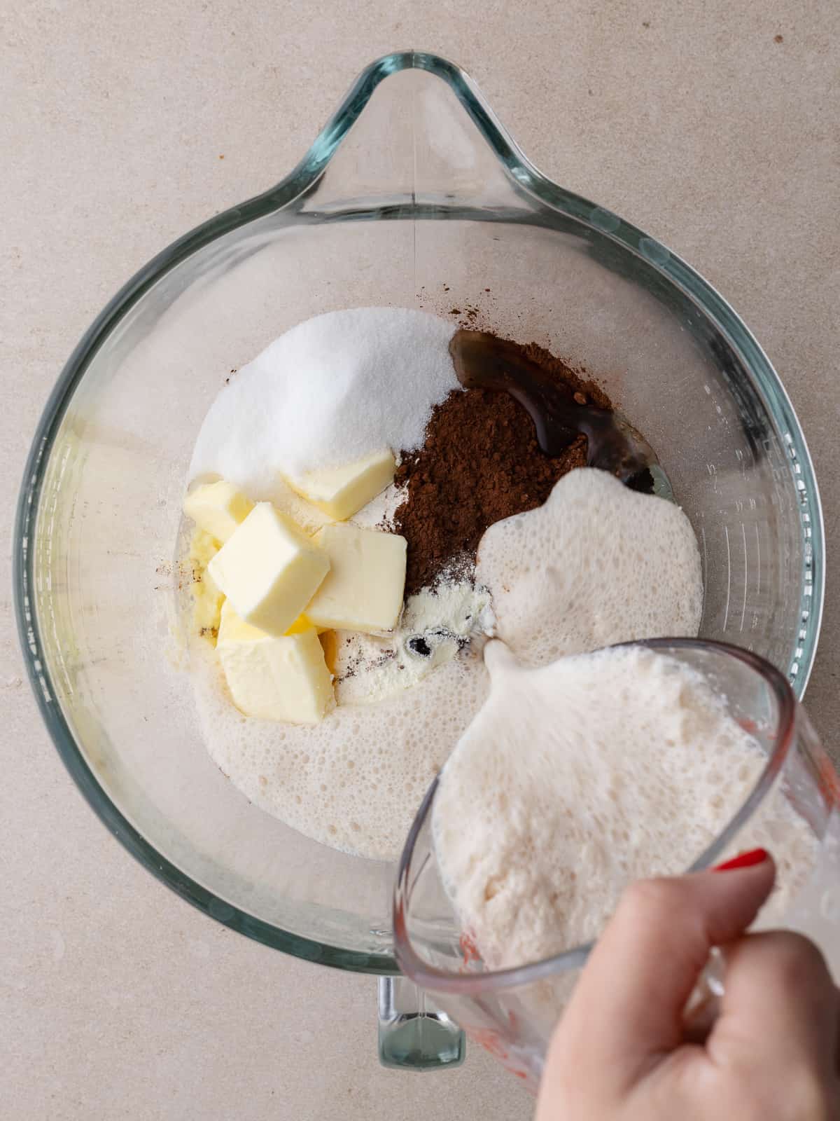 Flour, cocoa powder, sugar, butter, vanilla, milk powder, eggs, and yeast mixture in a glass mixing bowl