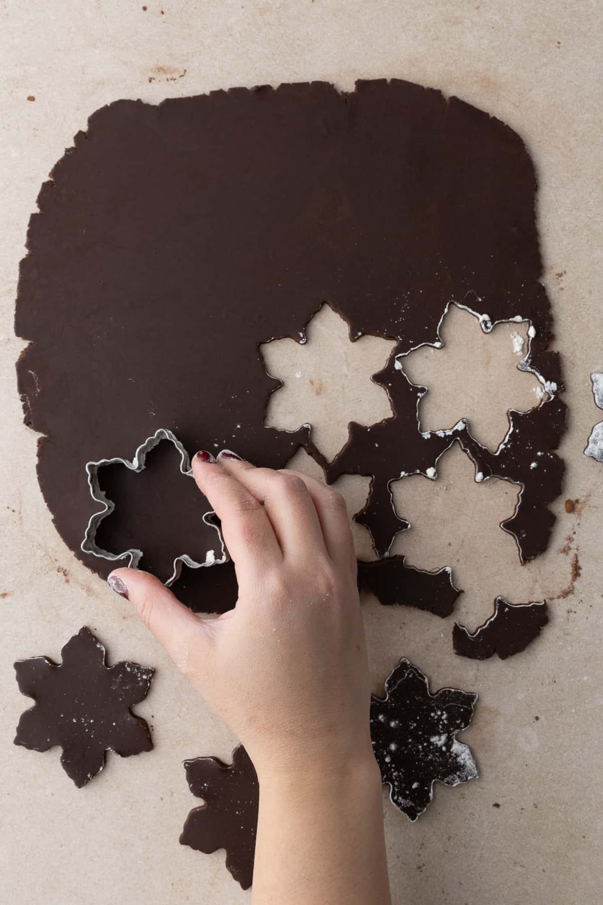 Cutting out snowflake cookies with rolled out cookie dough