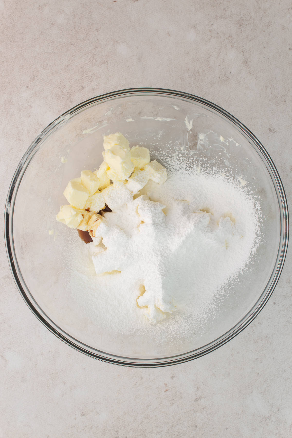 Butter, powder sugar and vanilla are in a glass bowl