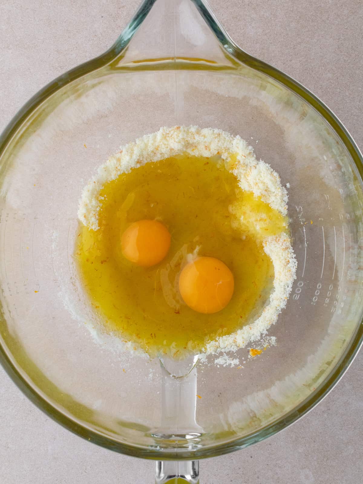 Two large eggs are added to a large bowl of sugar and orange zest.