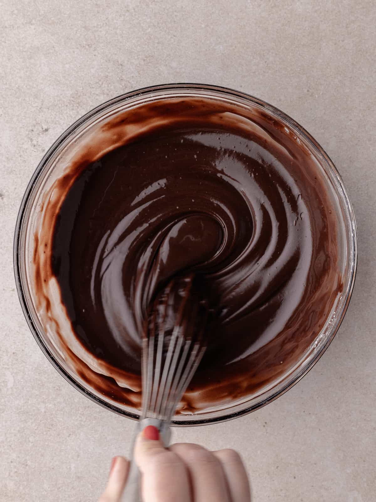 Chocolate is being whisked in a medium bowl.