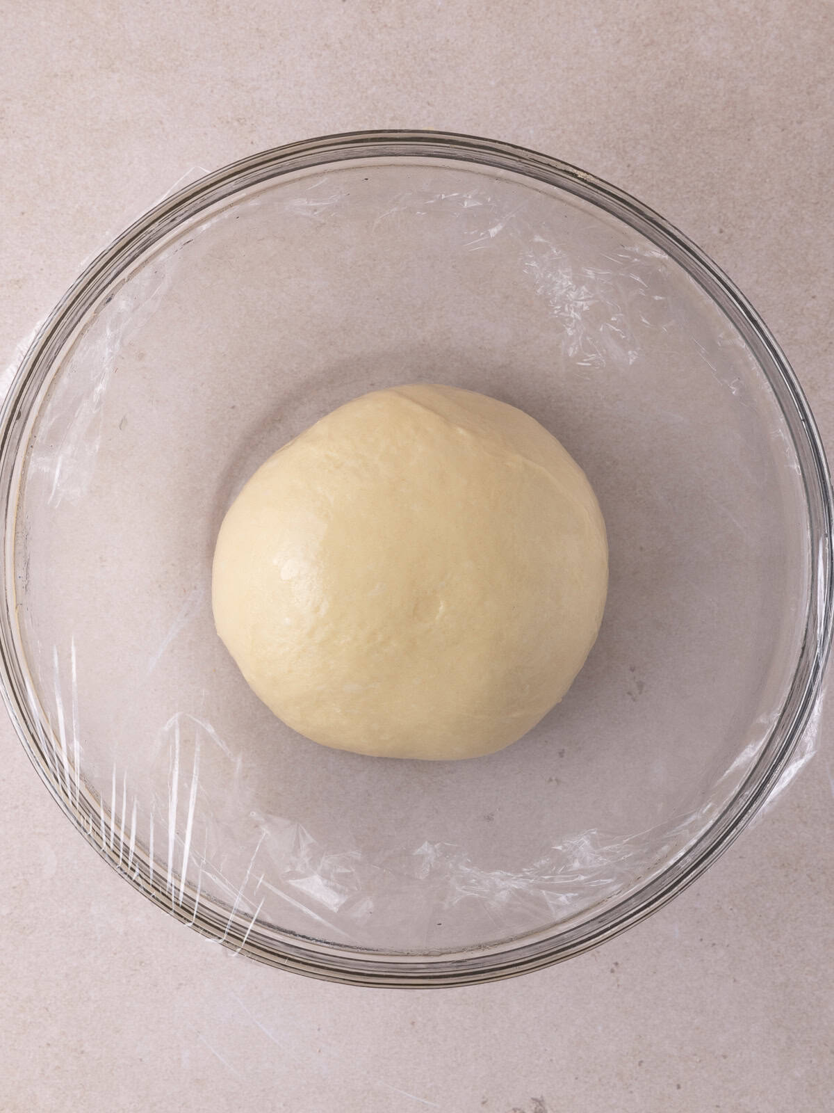Ball of dough in glass bowl before rise.