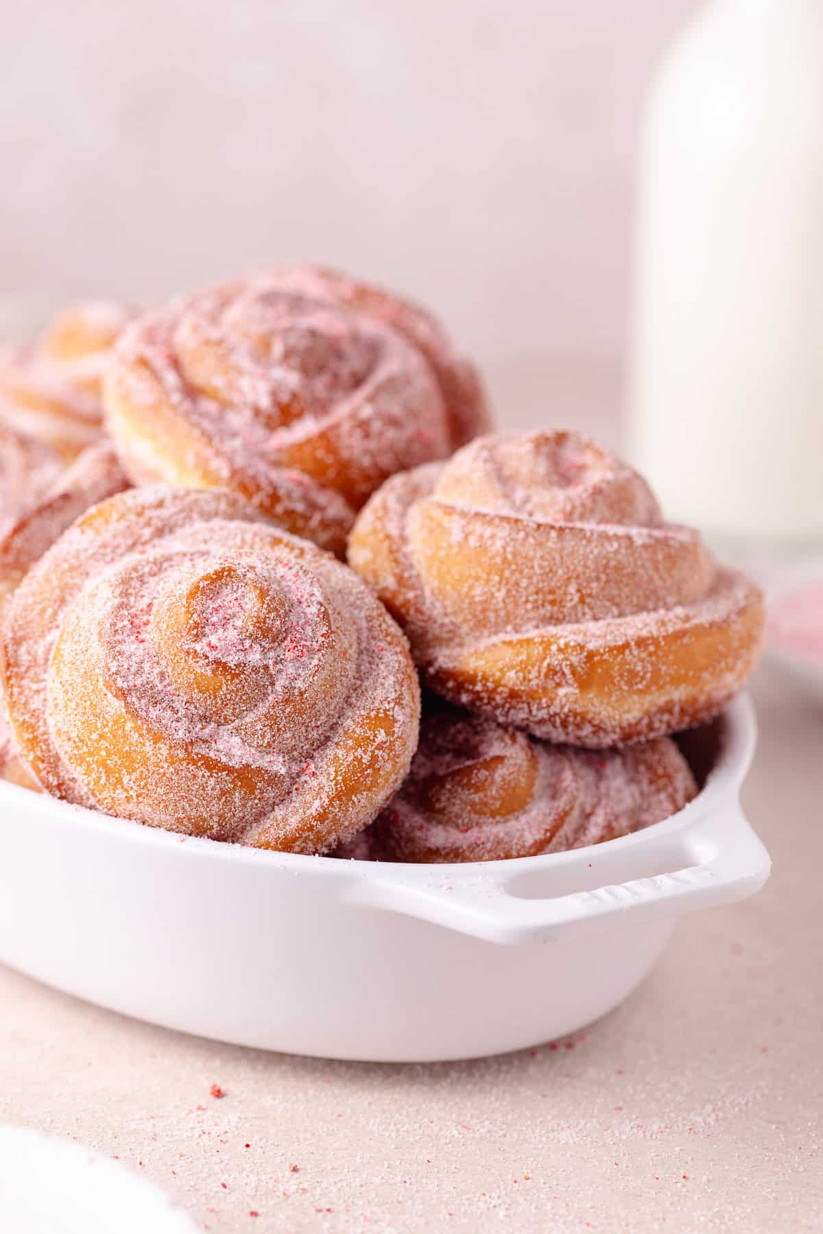 A pile of rose donuts in a baking tray.