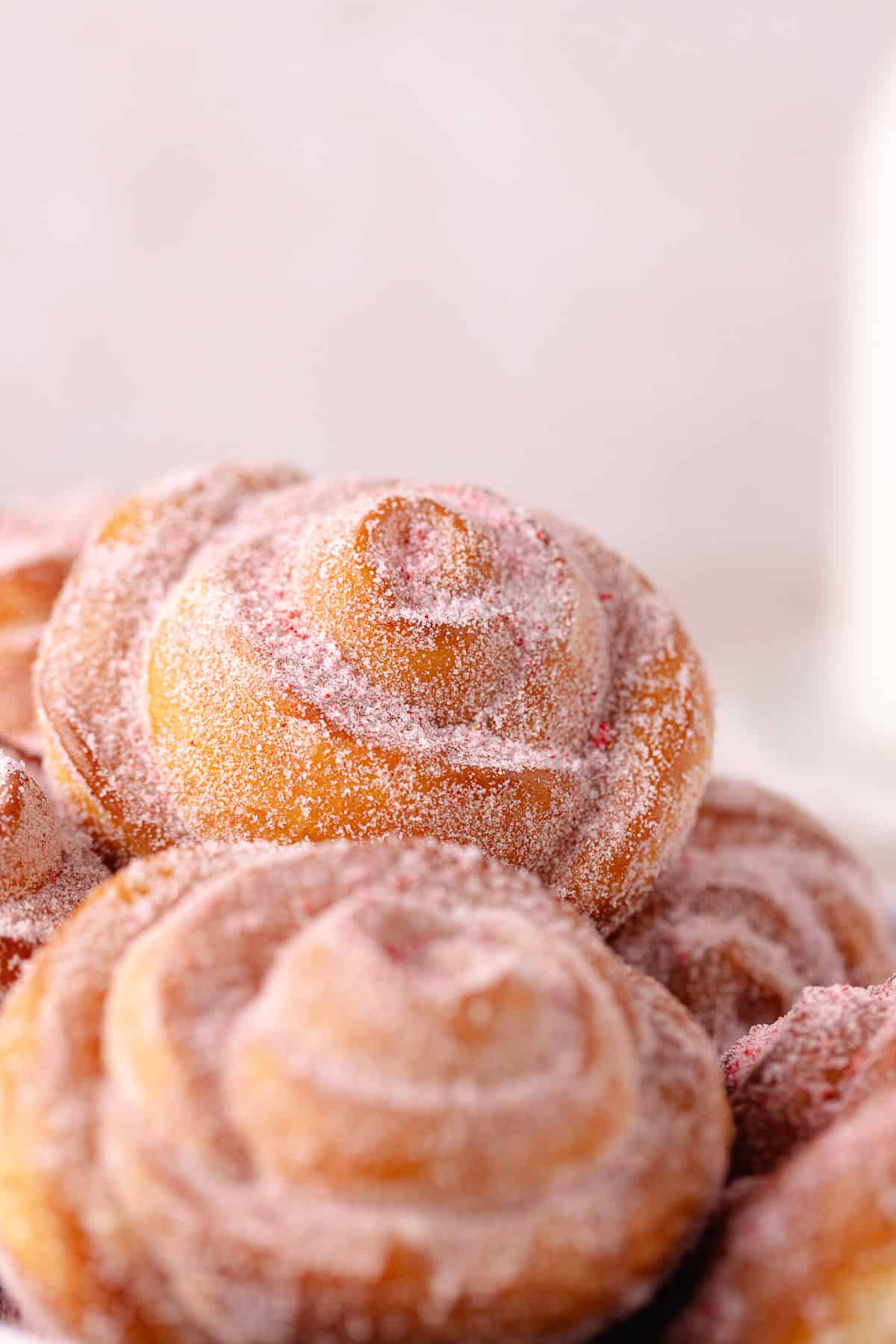 A close up of rose donuts in a baking tray.