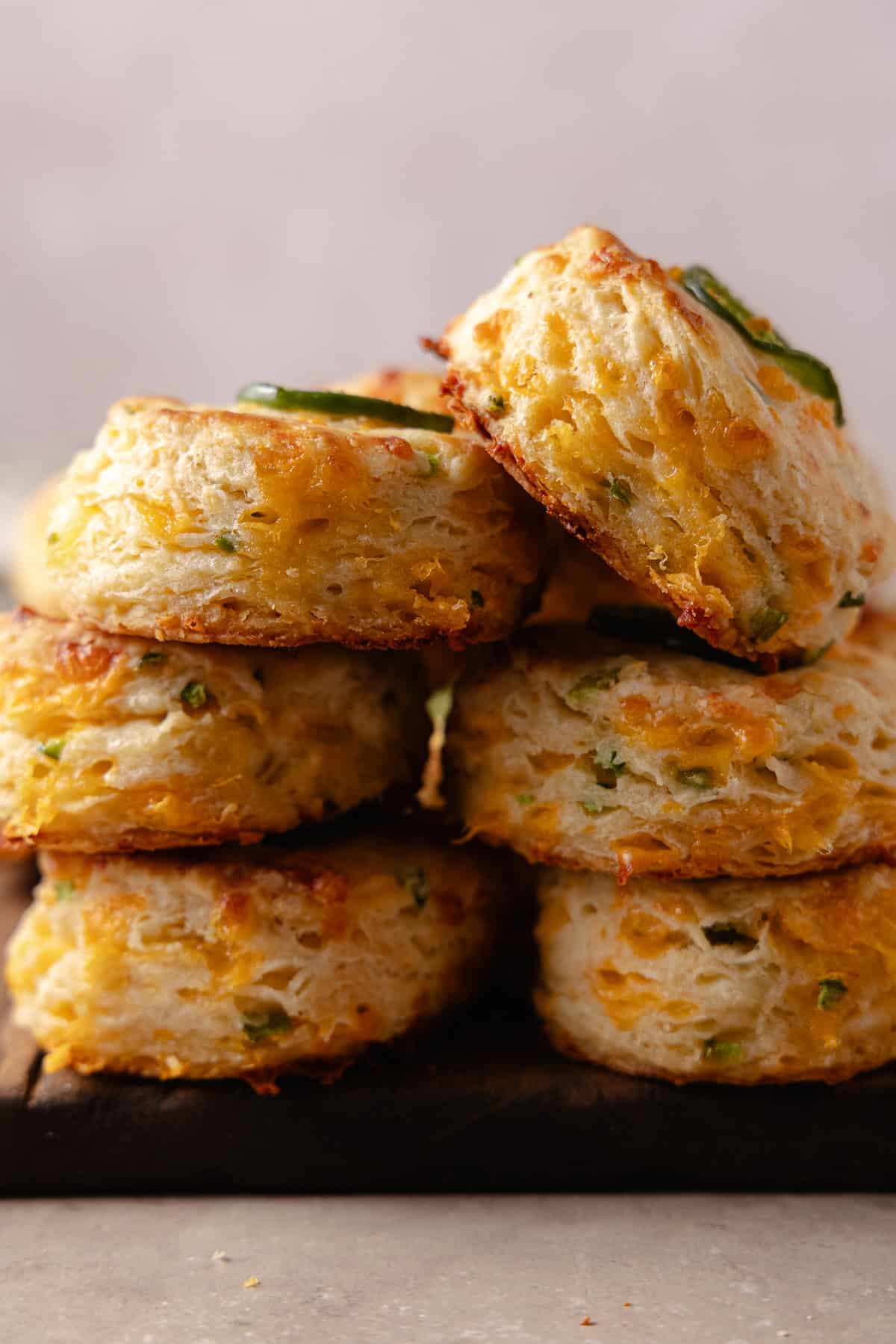 A pile of Jalapeno Cheddar Biscuits on a cutting board, showing off the flaky layers.