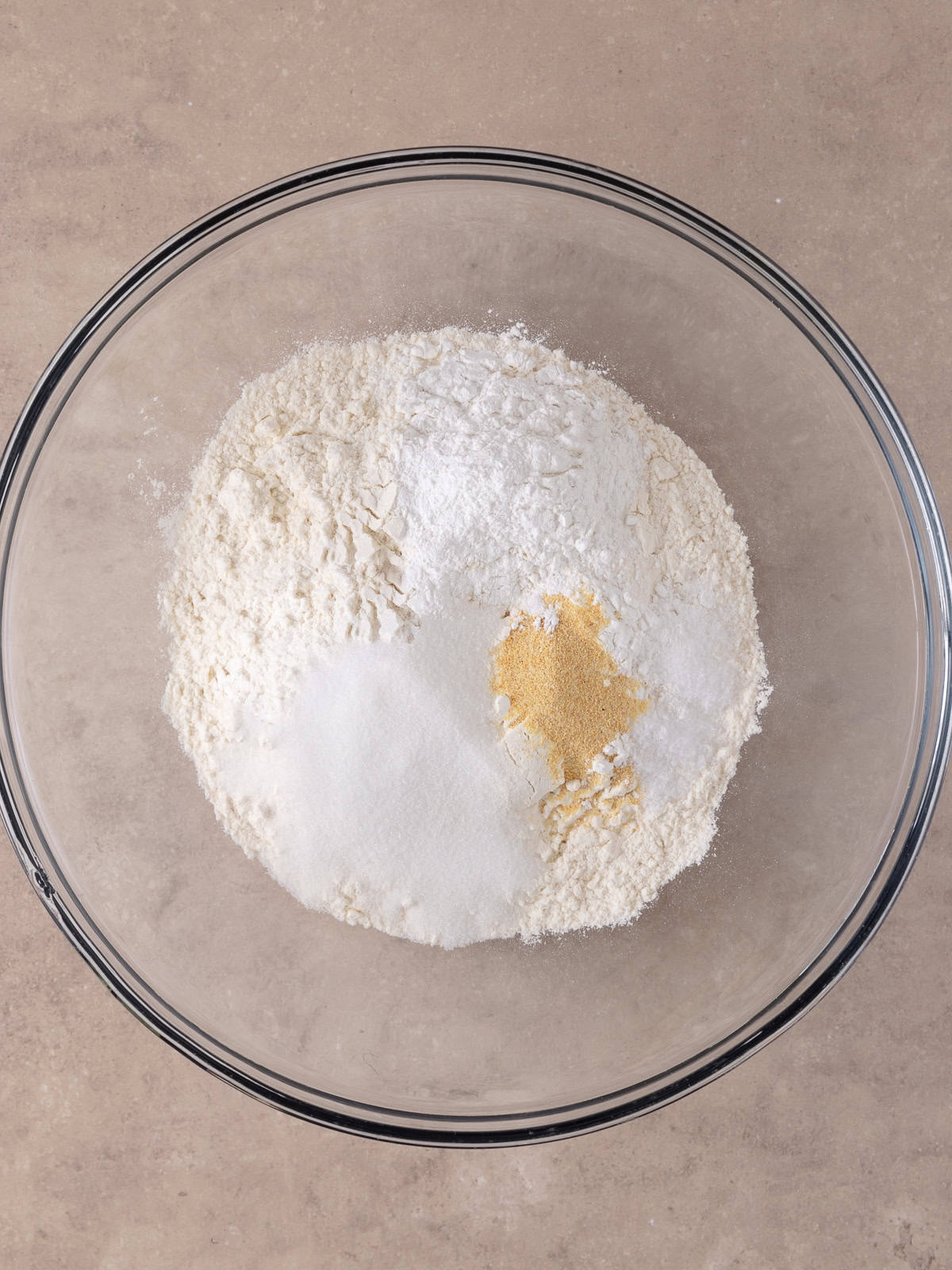 All purpose flour, sugar, baking powder, garlic powder, and salt are in a large glass bowl.