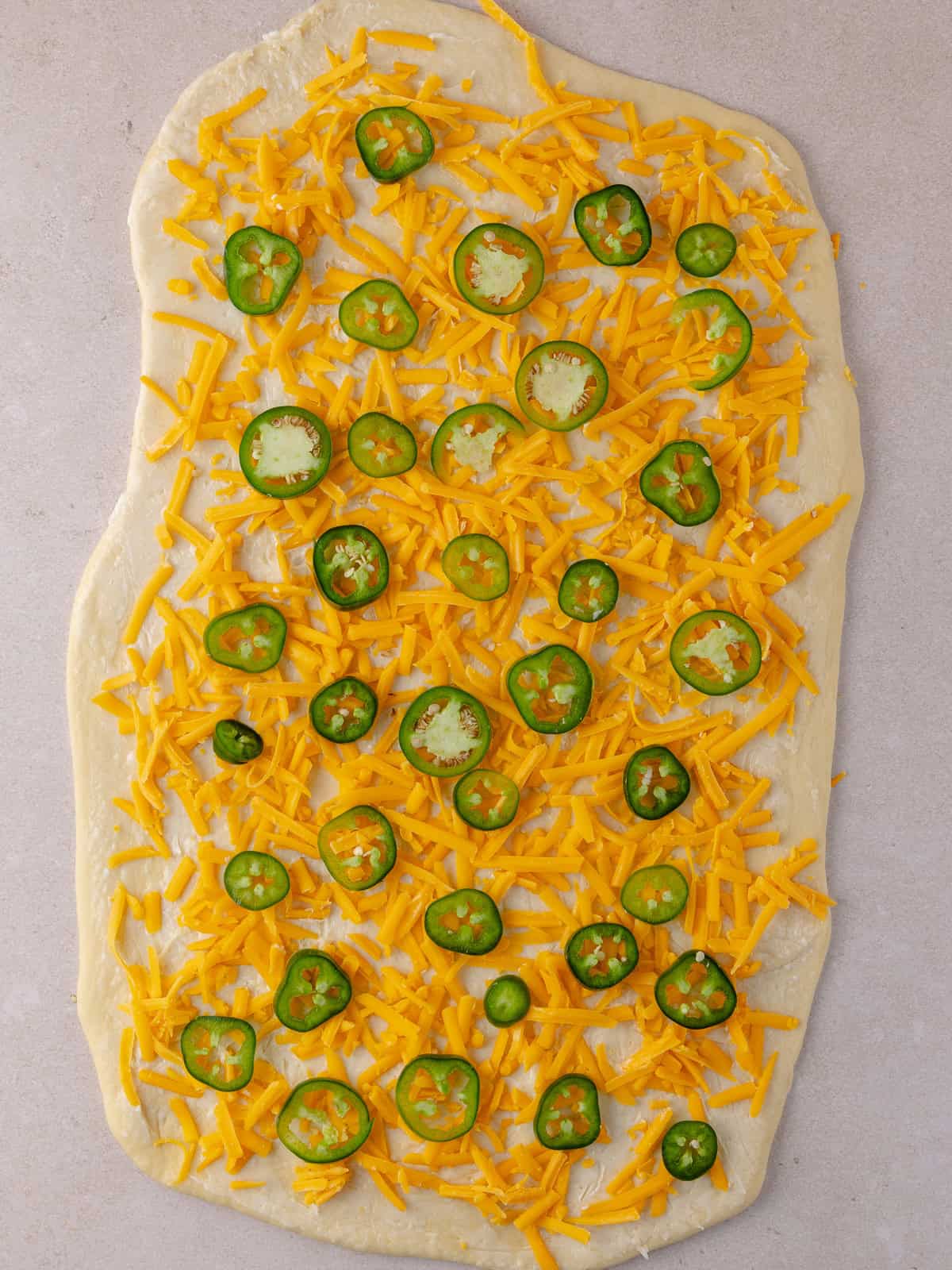 Shredded cheddar cheese and jalapenos are added on top of garlic butter layer.