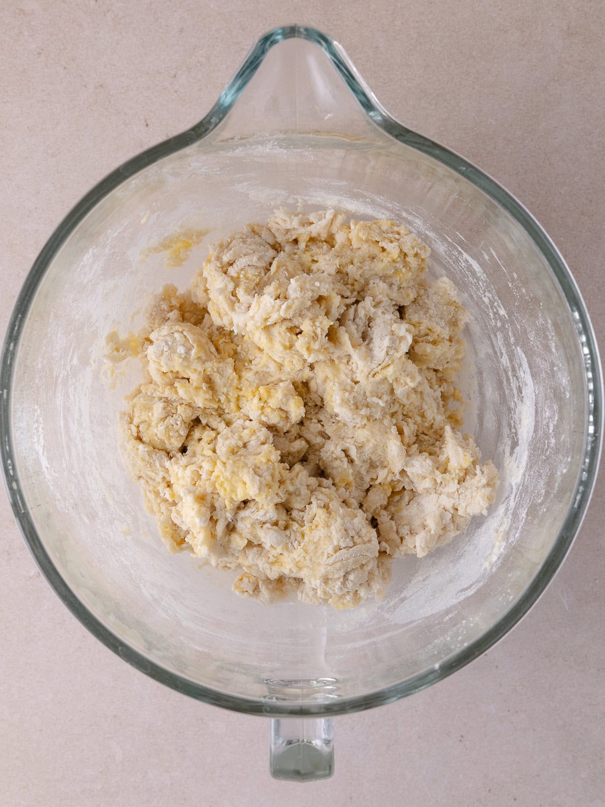 A shaggy ball of dough has been formed by mixing all the dough ingredients in a large mixing bowl.