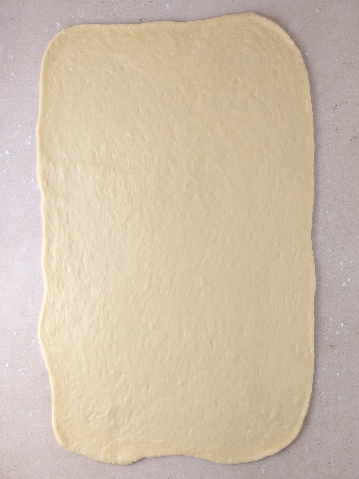 Dough has been punch down and rolled out to roughly a 16x24 inch rectangle.