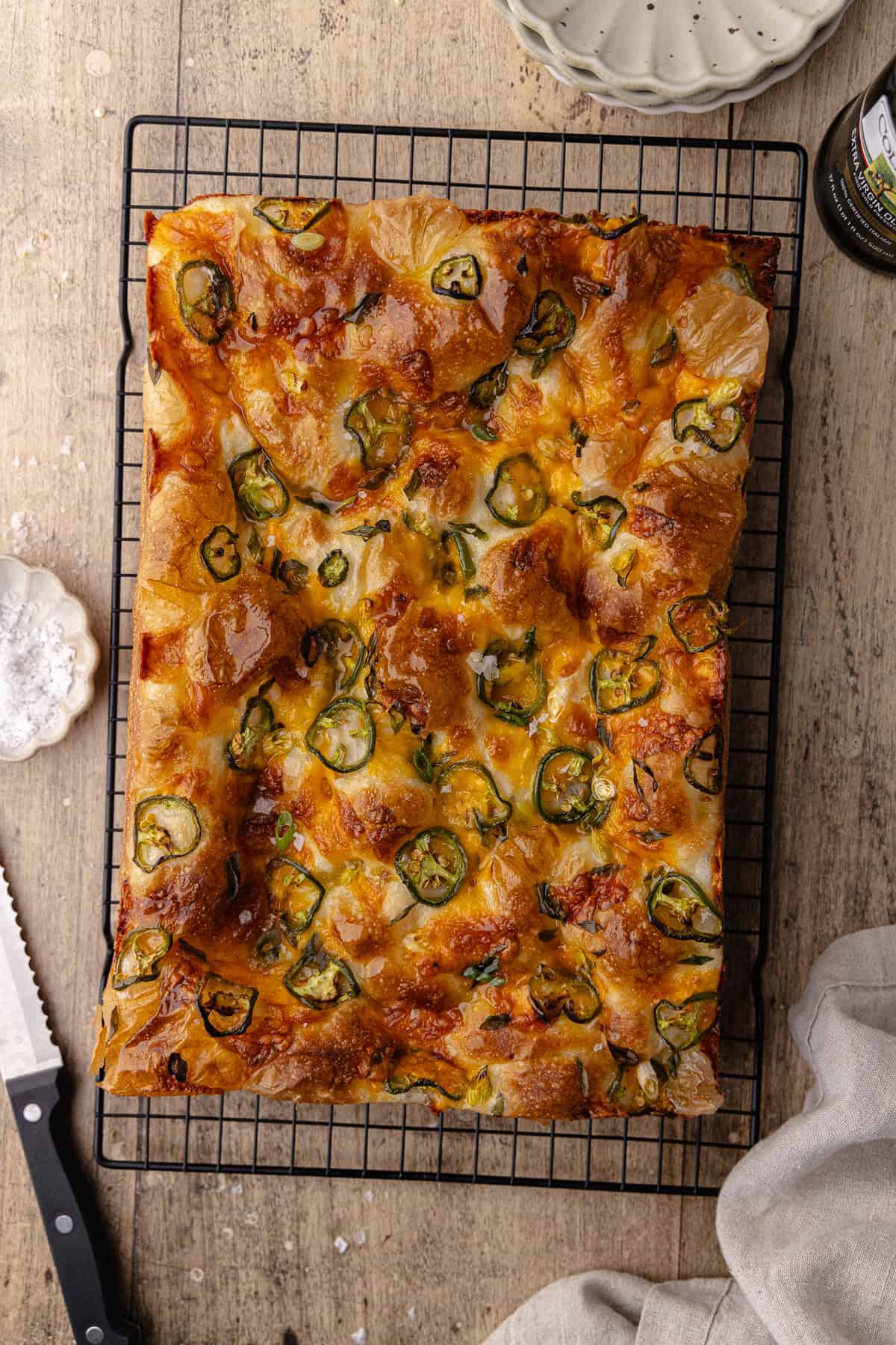 Jalapeño cheddar focaccia on a black cooling rack.