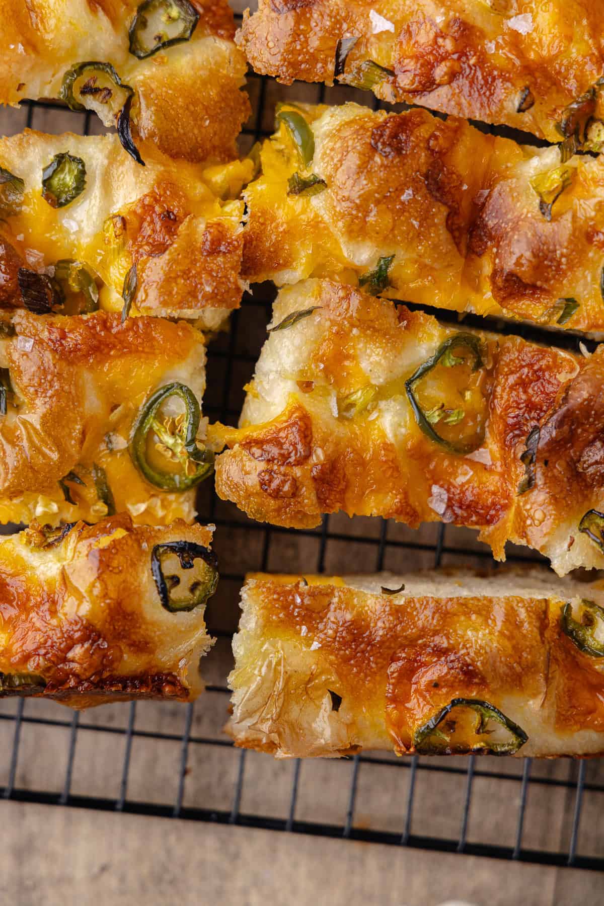 Slices of Jalapeño cheddar focaccia on a black cooling rack.