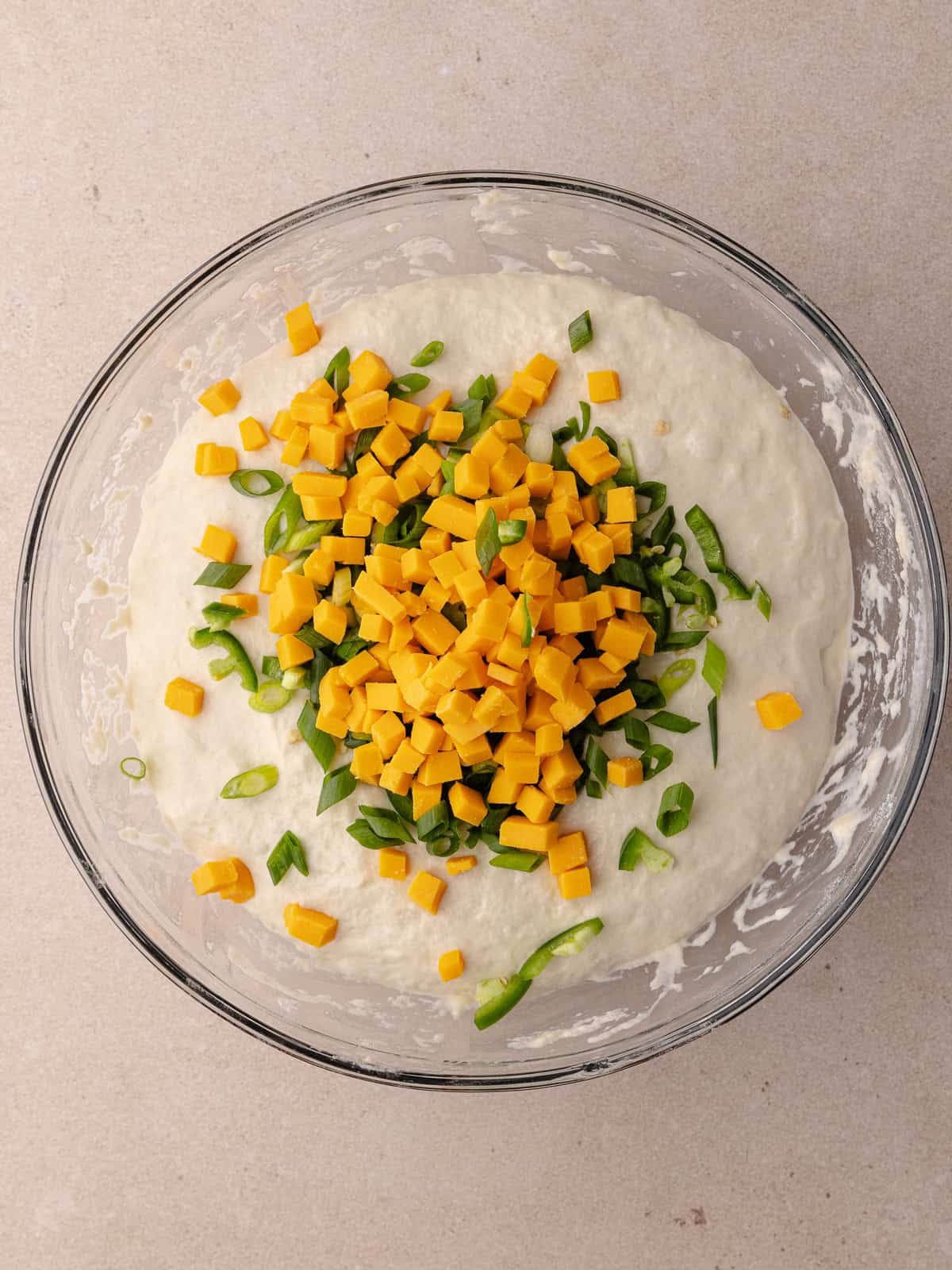 Sliced jalapenos, sliced green scallions and diced cheddar cheese is added to the ball of dough.