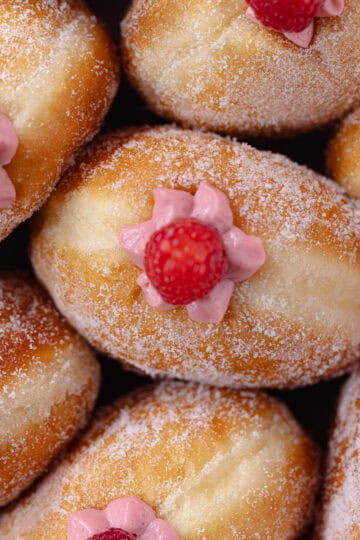 Raspberry cheesecake donuts sitting in a white baking dish feature photo.
