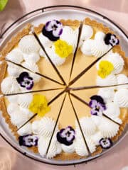 Easy lemon condensed milk tart with graham cracker crust, cut into slices and sitting on a serving plate feature photo.