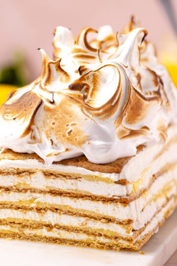 Lemon icebox cake with lemon curd and torched meringue topping on a serving plate featured photo.