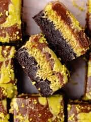 Pistachio brownies filled with kataifi pistachio cream filling are cut into squares and are sitting on a wire rack feature photo.