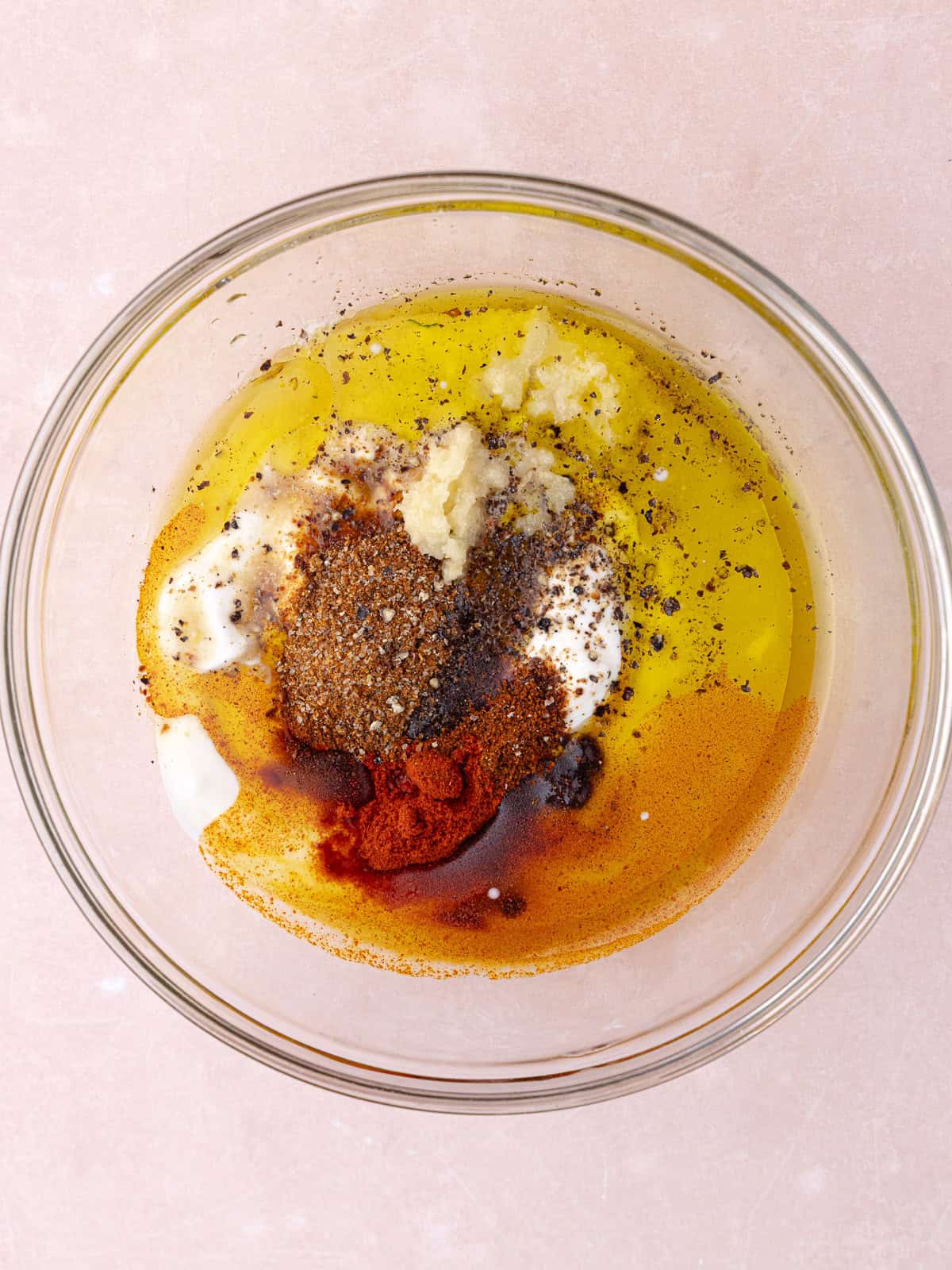 Greek yogurt, olive oil, lime juice, grated garlic, smoked paprika, chili powder, salt, pepper and chile lime seasoning are in a small glass bowl.