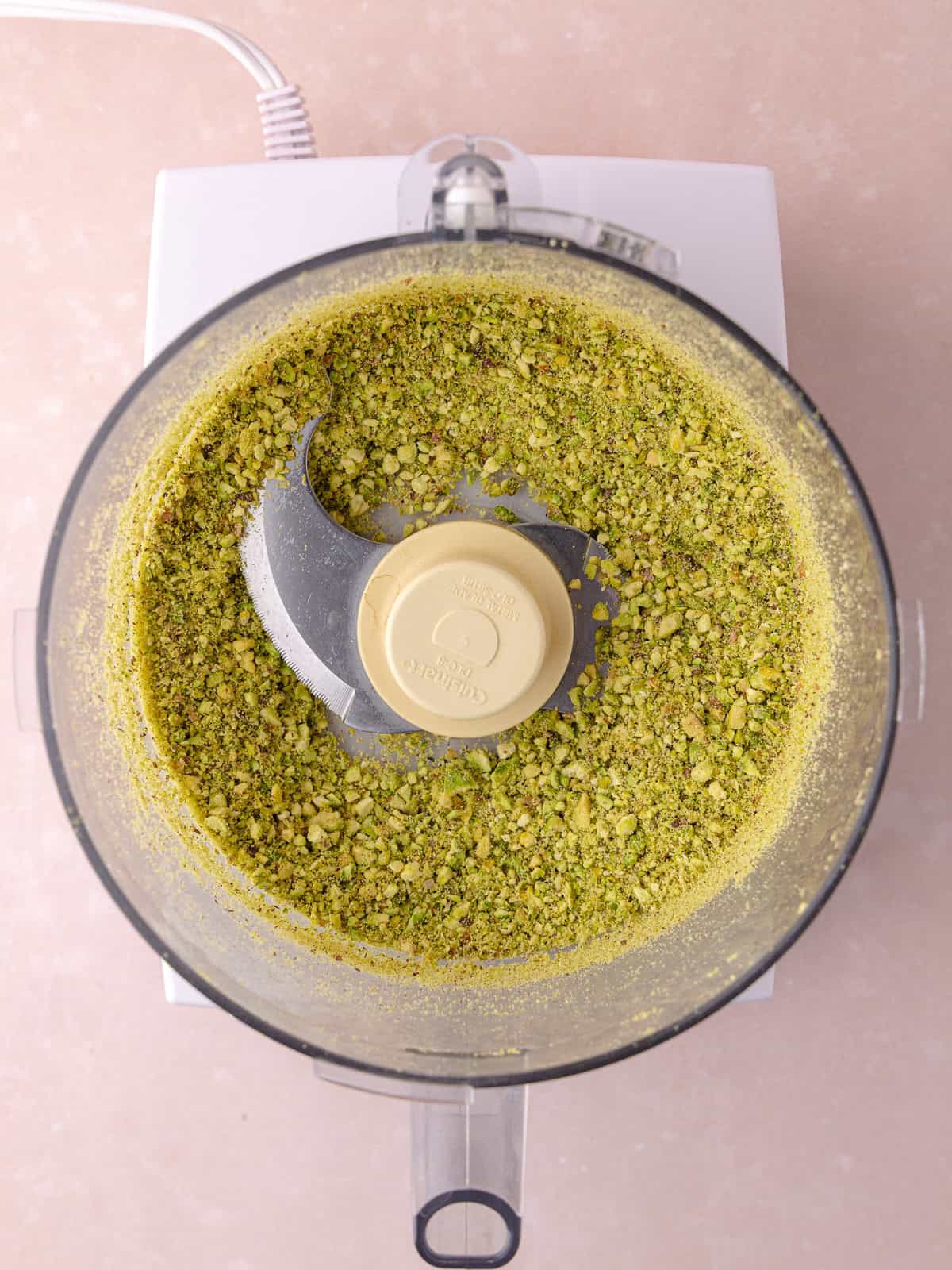 Pistachio nuts are processed in a food processor until roughly ground.