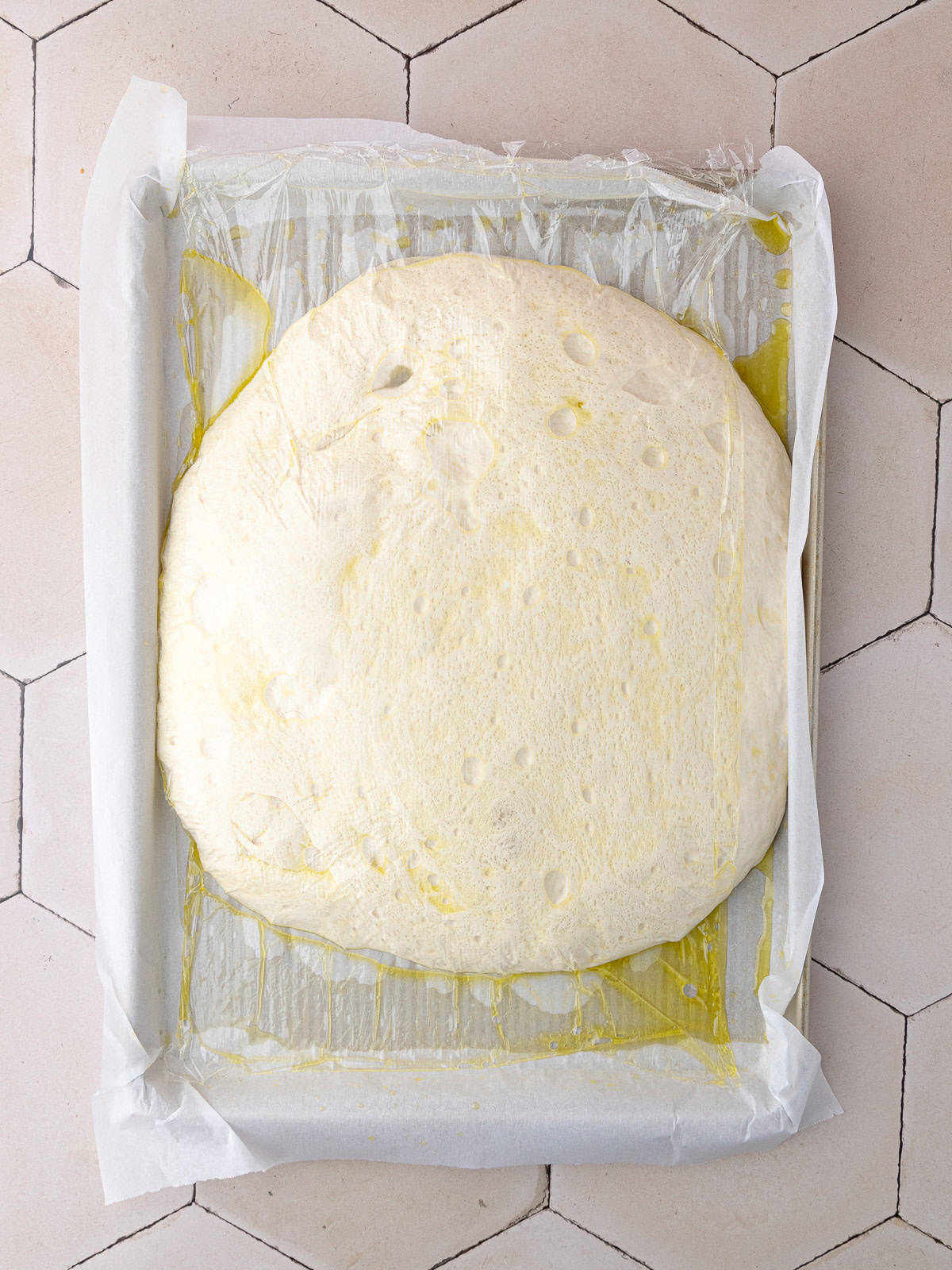 The dough sits at room temperature in a large baking sheet for 3 hours until doubled in size.