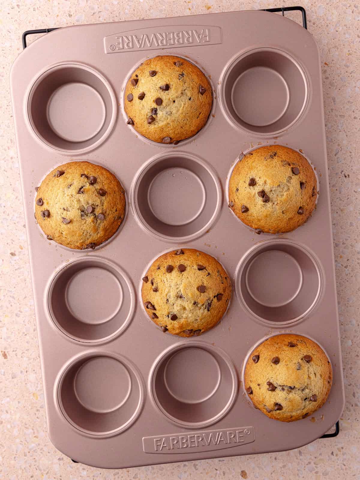A small batch of chocolate chip banana muffins are in a muffin pan.