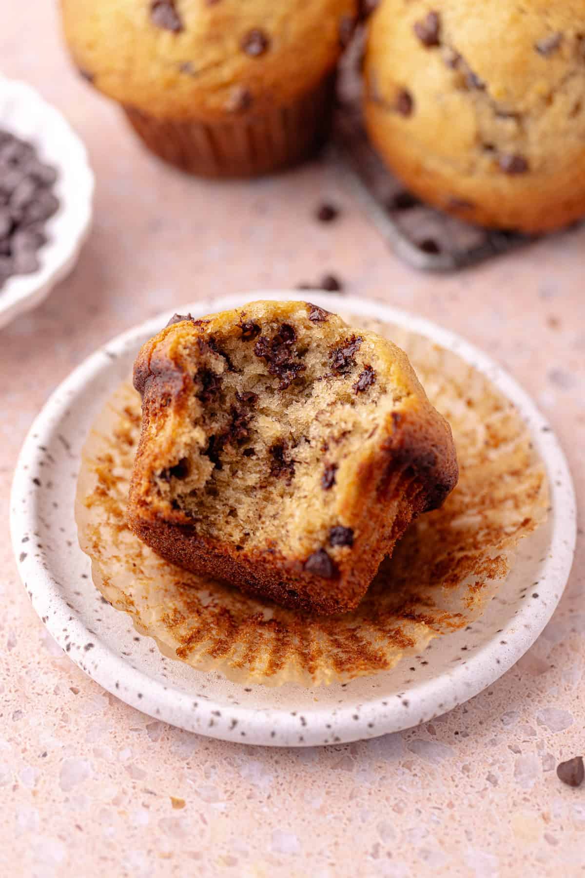 Super moist chocolate chip banana muffin sitting on a small dessert plate.