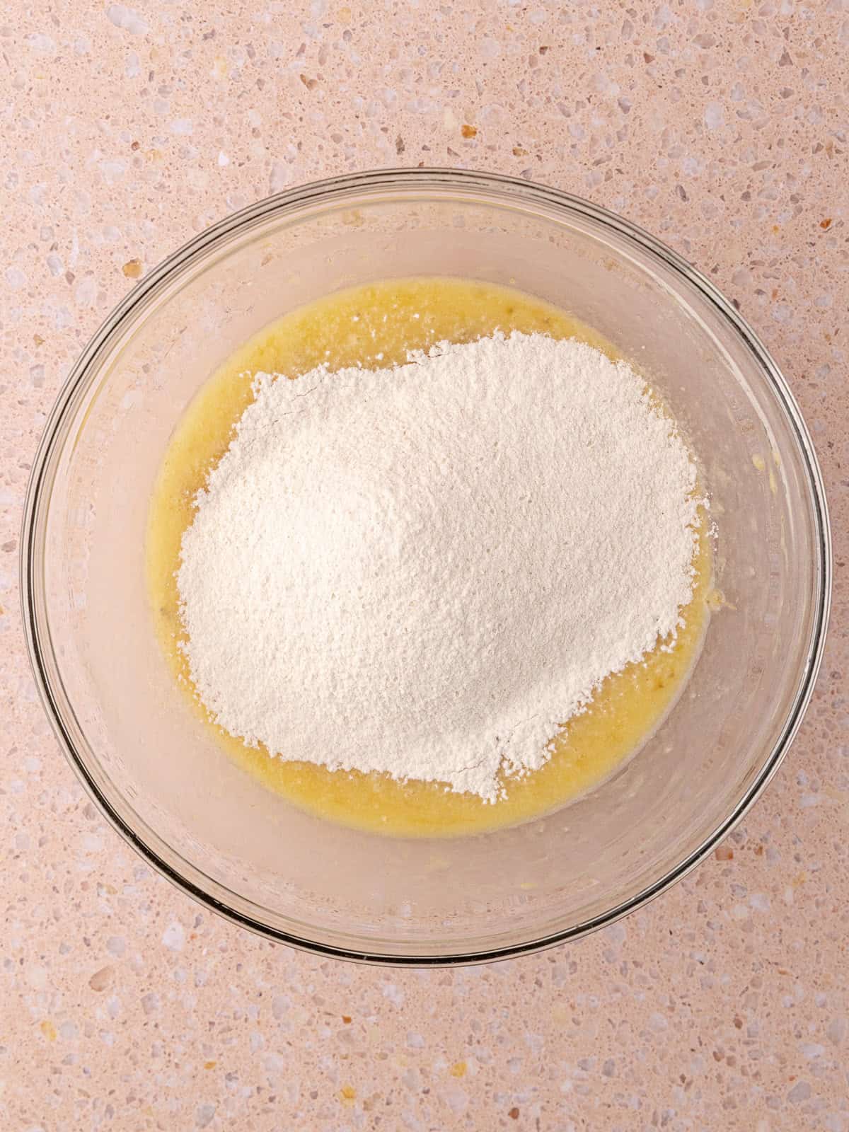 Flour mixture is added to the wet ingredients in a bowl.